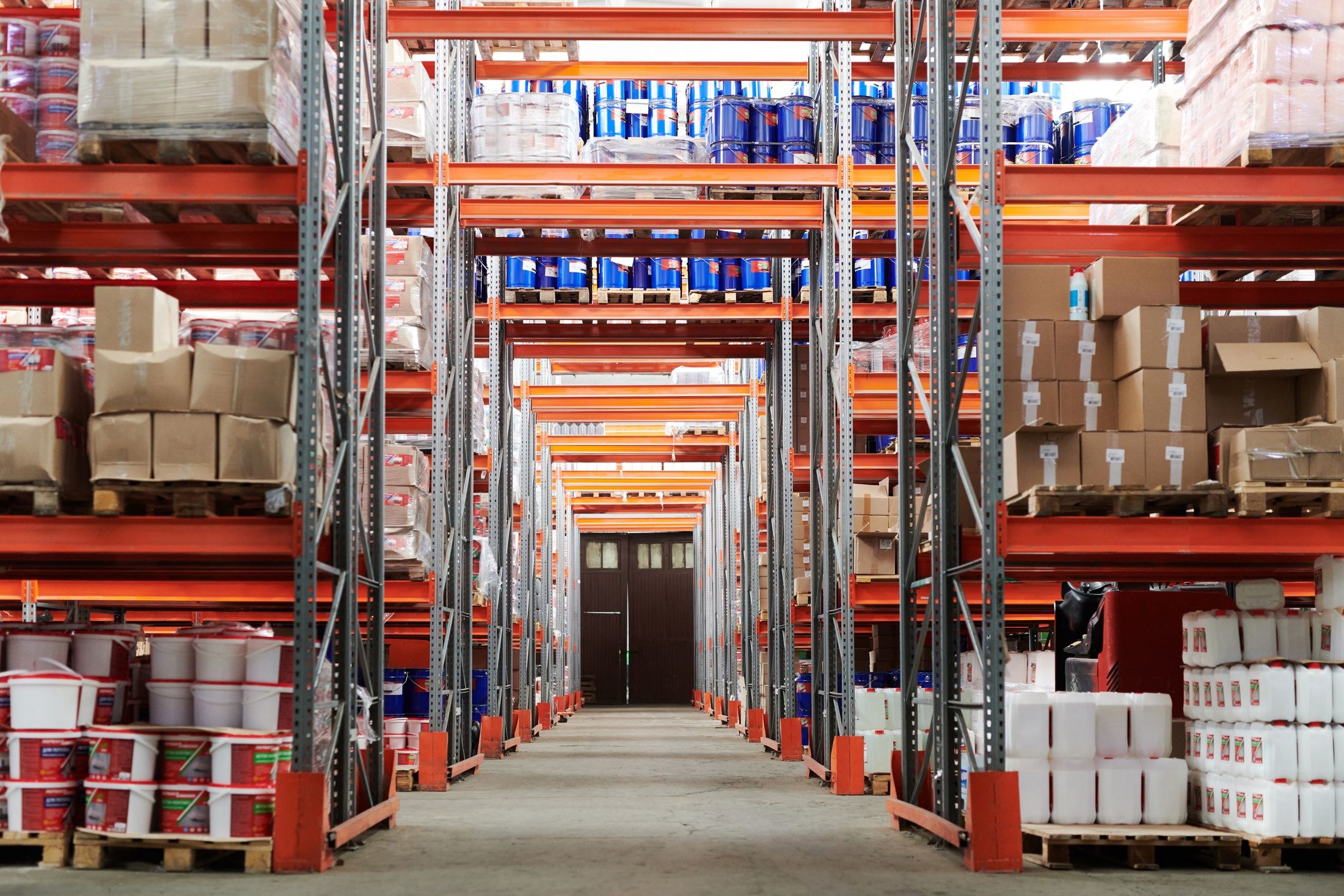 Stocked warehouse racks lining a central concrete aisle